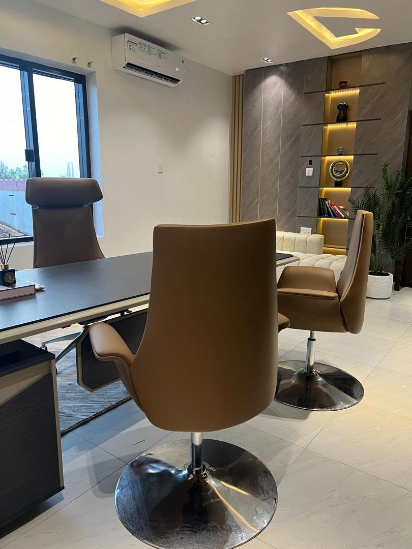 Executive office with tan leather chairs, marble wall and lit display niche